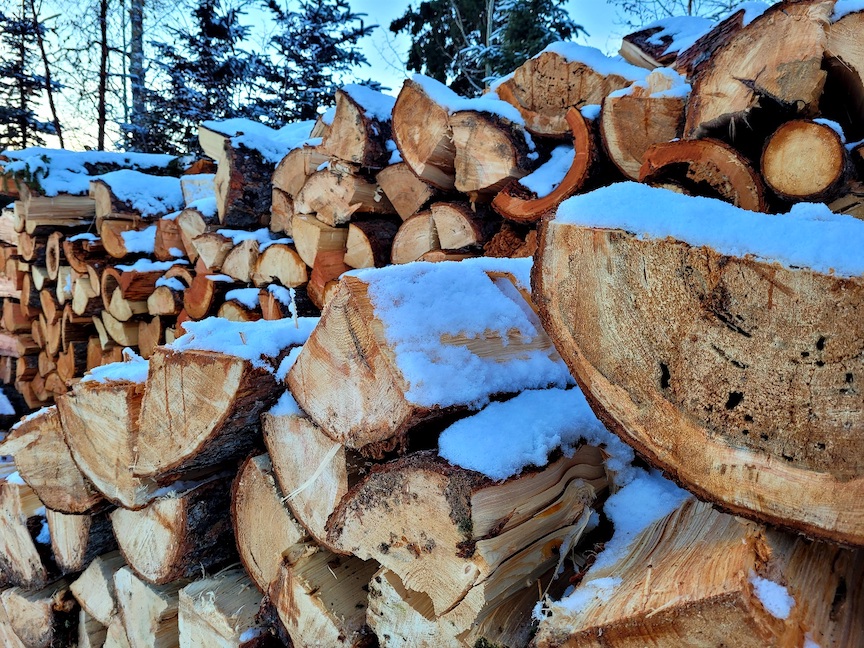 photo of a chopped wood pile 3 layers deep, dusted with snow