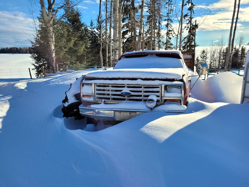 photo of an old Ford truck nearly buried in deep snow