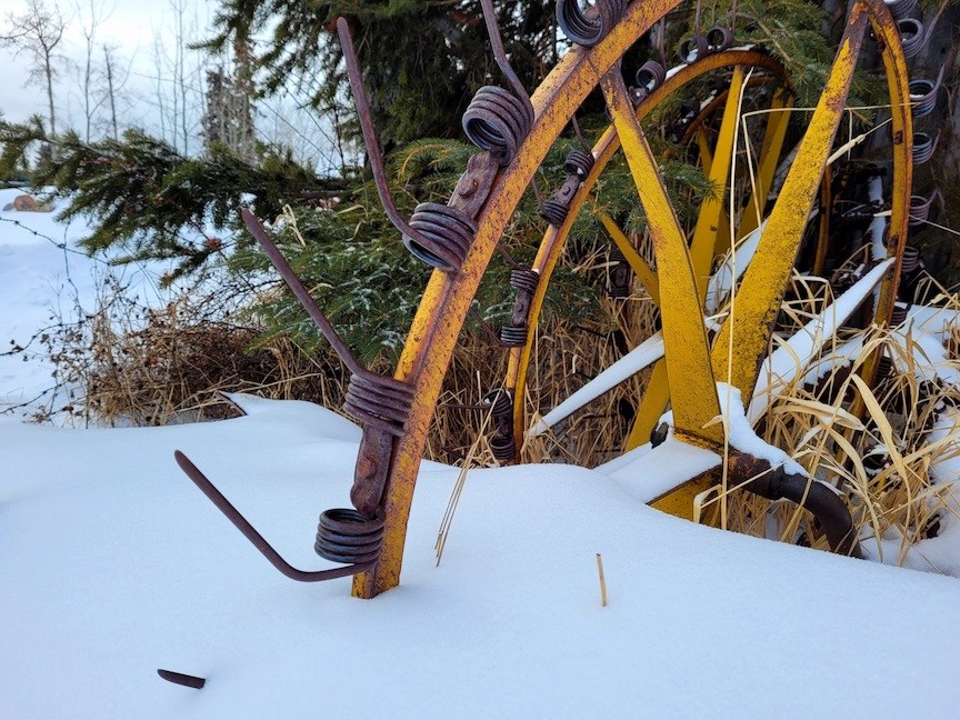 photo of a yellow baling wheel half buried in snow