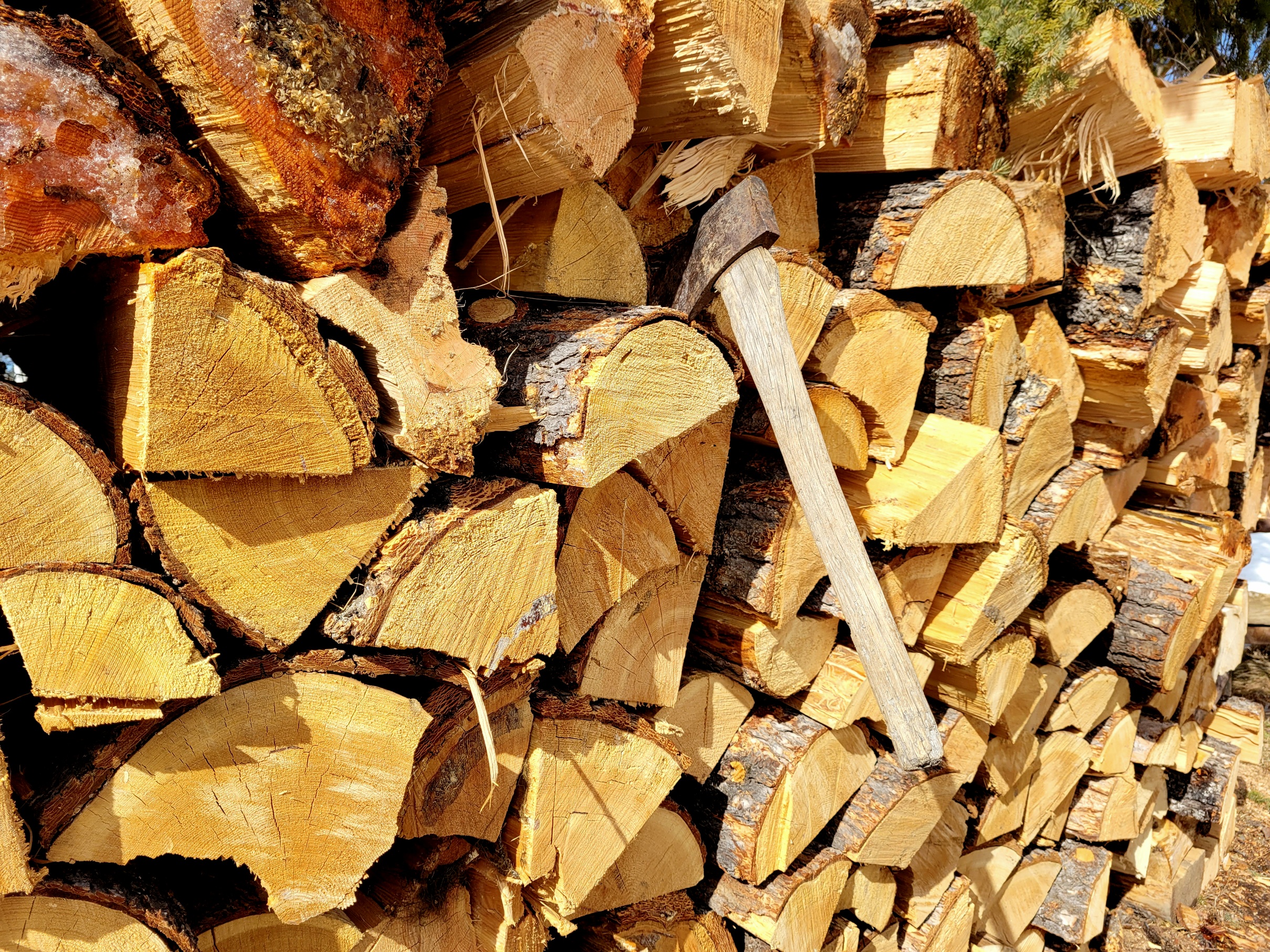 photo of a tall woodpile with an axe stuck into it