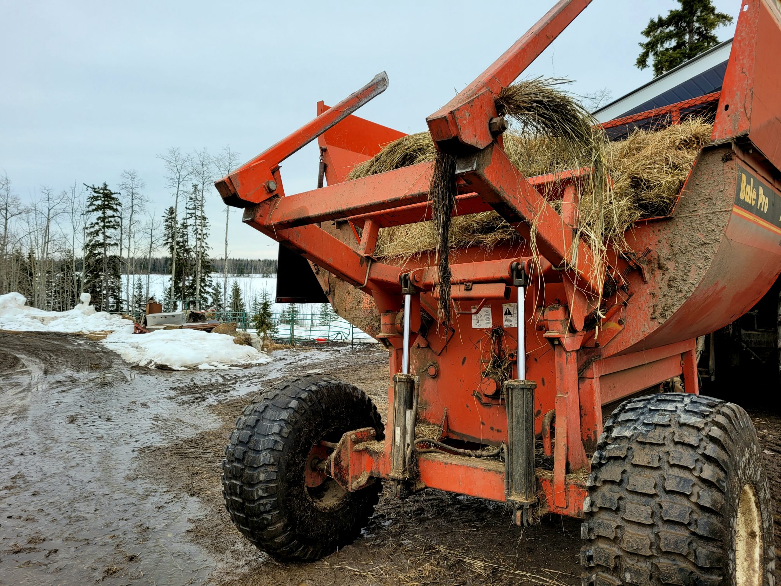 photo of a muddy hay baler surrounded by melting snow