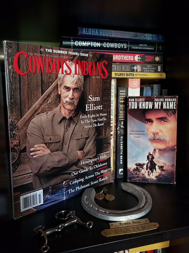 photo showing a bookshelf with a magazine featuring Sam Elliott and a Sam Elliott VHS tape