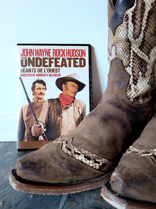 photo of The Undefeated DVD next to a pair of snakeskin cowboyboots