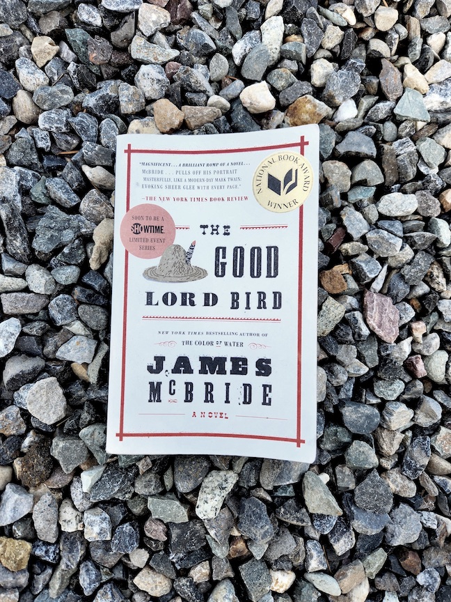 photo of The Good Lord Bird book against small rocks