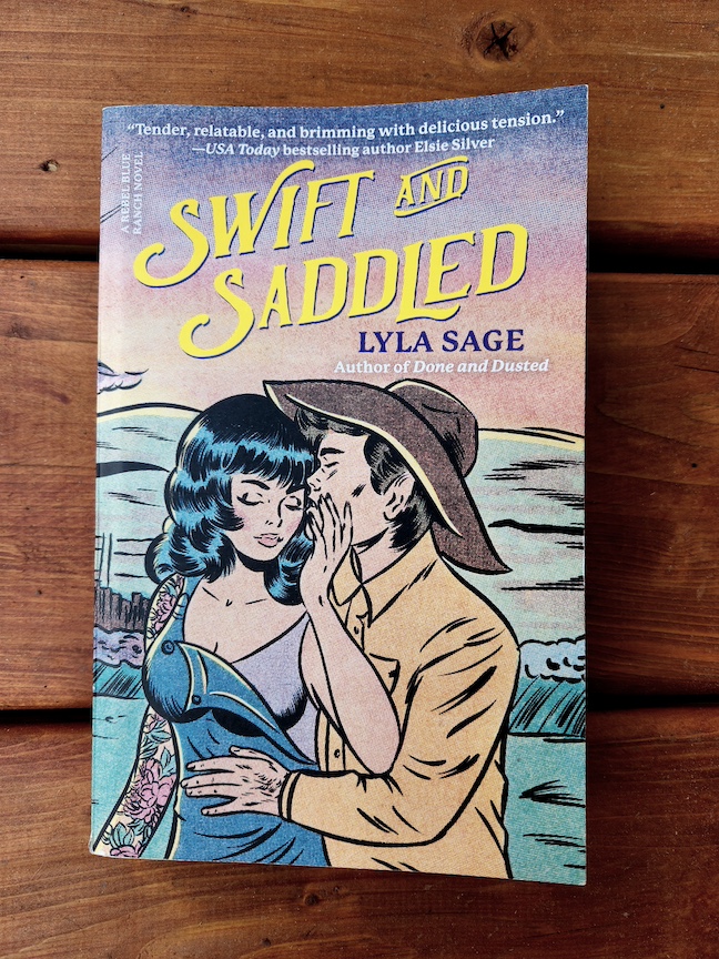 photo of Swift and Saddled paperback, against copper-stained deck slats