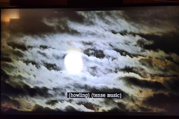 photo of a cloud-covered full moon with closed captions that read "howling" and "tense music"