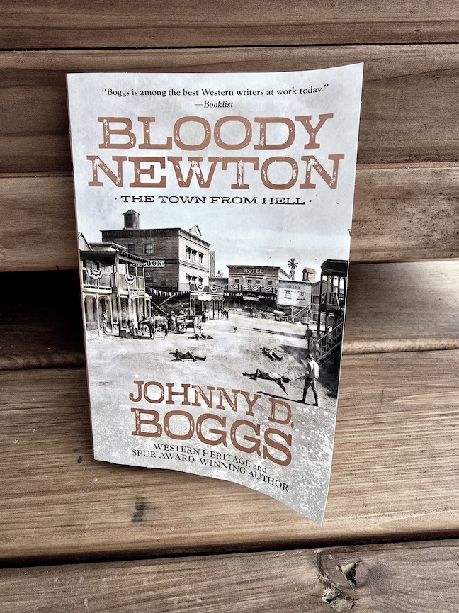 photo of the Bloody Newton book against a dark wooden porch