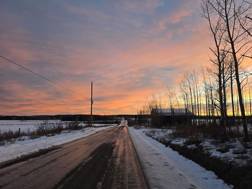 photo of a long private farm road covered in ice, in a glowing sunset