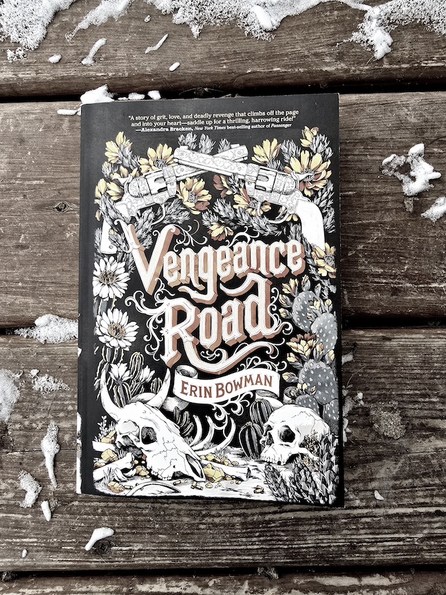 photo of the Vengeance Road paperback against slatted wood with snow at the edges